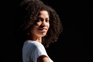 Kıvırcık siyah bir kadının yaz ortasında komik bir portresi. Yaz mevsimindeyiz ve o doğrudan kameraya bakıyor..