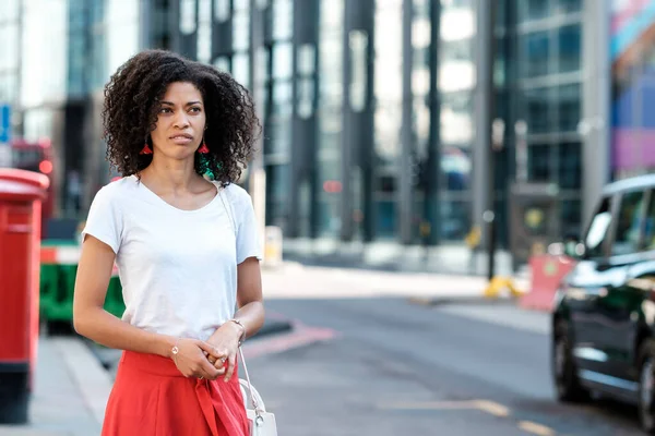 Londra caddesinde duran siyah kadın mutsuz görünüyor. O birini bekliyor. Büyük şehirlerde stres ve kirlilik.