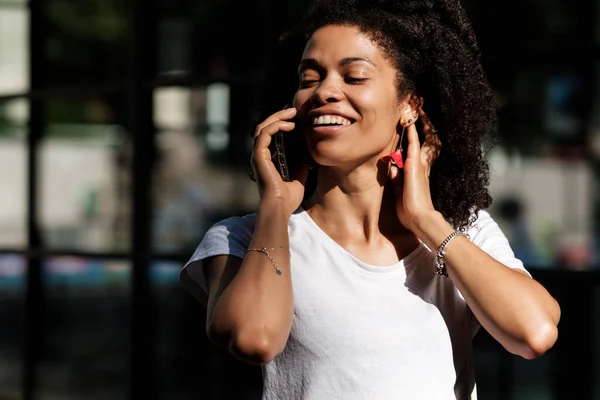 Улыбающаяся Кудрявая Женщина Разговаривает Телефону Лондонской Улице Выглядит Действительно Счастливой Стоковое Изображение