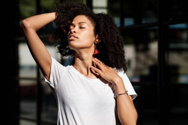 Street portrait of curly black model in London. Her eyes are closed and she looks really relaxed. Summer vibes and harsh light. clipart