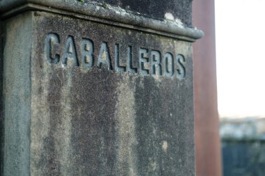 Kullanılmış taştan bir sütunun yakın görüntüsü. Kabarcıklar oyulmuş, ispanyolca erkekler tuvaleti anlamına geliyor ve geleneksel bir cazibe katıyor.