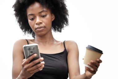 İzole edilmiş bir kadın telefon kullanıyor ve elinde bir fincan kahve tutuyor. Eğlence amaçlı takip konsepti. İşten izin al..