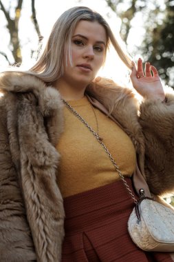 Kış ormanlarındaki kadın modelin nostaljik portresi. Eski moda ve romantik bir modda poz veriyor. Doğruca kameraya bakıyor ve sahte kürk manto giyiyor..