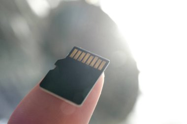 Arka lambalı bir parmakta mikro SD kart var. Teknoloji ve dijital depolama konsepti. Makro fotoğrafçılık.