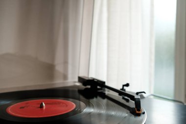 Turntable ve vinil. Pencerenin yanında doğal ışık var. Otantik ve eski moda müzik hobileri.
