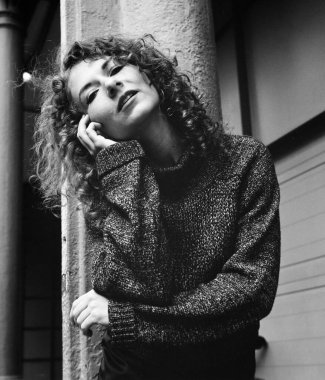 Kadın modelin açık hava manzaralı portresi. O bir sütuna yaslanıyor ve sağ eli yanağında. Bir analog film orta formatlı kamera ile yapılmış tek renkli portre.