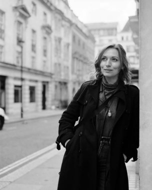 Analog B & W, Londra 'da binaya dayanan kadın portresi. Gülümsüyor ve başka tarafa bakıyor. Klasik görünüş ve kumlu film, görüntü orta formatlı film kamerası ile çekildi.