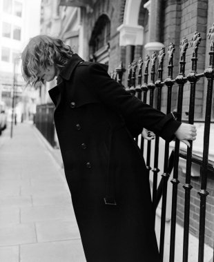 Parmaklıkları tutan ve sokağa yaslanan tanınmamış bir kadın. Bu tek renkli bir görüntü, bir film analog orta format kamerasıyla yapılmış. Londra sokakları.