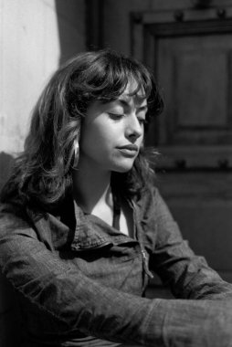 Siyah beyaz bir portrede duvara yaslanan dalgın genç bir kadın. Rahatlamış görünüyor ve başka tarafa bakıyor. Görüntü 35 mm analog film kamerası ile yapıldı.