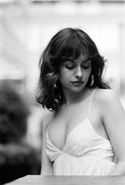 Romantik siyah beyaz kadın portresi. Şehvetli beyaz bir yaz elbisesi giyiyor. Eski bir kamerayla yapılan analog bir film görüntüsü. Aşağıya bakıyor..