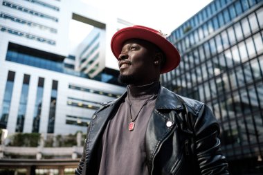 Londra 'nın kozmopolit bölgesinde modern binalarla çevrili erkek modelin yan görüntüsü. Kırmızı bir el ve siyah deri ceket giyiyor..