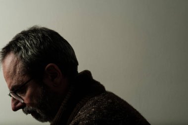 Üzgün, olgun bir adam yalnızlık ve depresyon gösteriyor. Duvara yaslanmış ve gözlük takıyor. Akıl hastalığı ve akıl sağlığı konsepti.