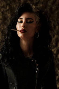 Havalı rock yıldızı kadın dışarıda sigara içiyor. Deri siyah bir ceket, büyük küpeler ve ağır bir makyaj giyiyor. Kameraya kendinden emin bir şekilde bakıyor..
