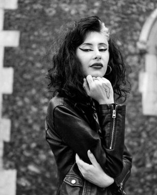 Dışarıdaki otantik genç bayanın klasik siyah beyaz portresi. O, siyah bir deri ceket ve ağır bir makyaj giyiyor. Analog film görüntüsü orta biçimli kamera ile yapılır.