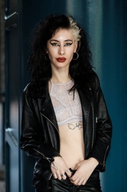 Mavi arka planda otantik bayan rock yıldızının portresi. O, siyah deri elbise ve beyaz üst artı ağır makyaj giyiyor. Gururlu duruş ve tavır.