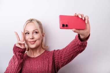 Genç nüfuzlu biri akıllı telefonuyla selfie çekerken barış ve pozitiflik mesajlarını sosyal medya platformlarına yayıyor.