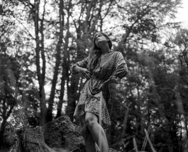 Tek renkli orta formatlı bir film. Genç bir kadının ormanda bir kayanın üzerinde görünür bir film tahıllı elbise giydiği bir fotoğraf.