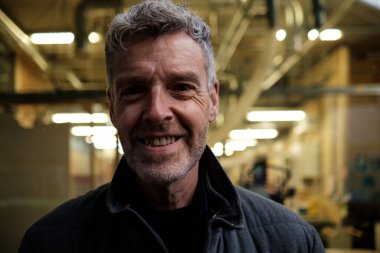 Fabrikada, endüstriyel ortamda gülümseyen gri saçlı mühendis imalat ve mühendislik alanında güven ve uzmanlık gösteriyor.