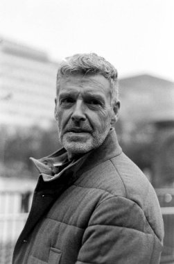 Grainy monokrom analog film portresi stil sahibi, son sınıf bir adamın örtülü bir ceket giymesi, kendine güveni ve sonsuz cazibesi.