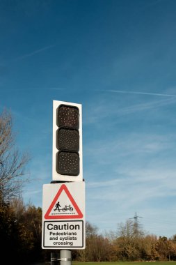 Kırmızı trafik ışığı, açık bir günde açık mavi gökyüzüne vurulan yaya ve bisikletçi geçişinde yol güvenliğini ve farkındalığı artıran bir uyarıda bulunuyor.
