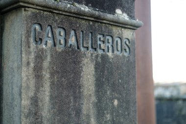 Kullanılmış taştan bir sütunun yakın görüntüsü. Kabarcıklar oyulmuş, ispanyolca erkekler tuvaleti anlamına geliyor ve geleneksel bir cazibe katıyor.