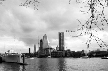 Tahıllı tek renkli 35 mm 'lik film fotoğrafı Londra ufuk çizgisini Hms Belfast, parça ve çıplak ağaç dalları ile yakalıyor nehir thames çerçeveli