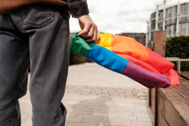 Igbtq + gurur, eşitlik ve çeşitliliğin sembolü olan bir gökkuşağı bayrağı elinde bulunduran kişi, toplumun kabulünü ve görünürlüğünü destekliyor.