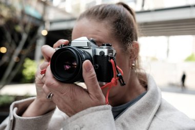 Fotoğrafçı klasik film fotoğrafçılık teknikleriyle bir anı yakalamak için kentte kırmızı kayışlı 35 mm 'lik klasik bir analog kamera kullanıyor.