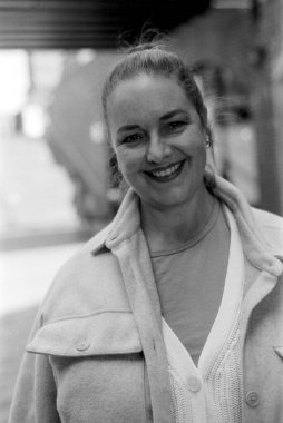 Kasvetli monokrom portresi, rahat kıyafetler ve rahat bir hırka giymiş, rahat bir atmosferde neşe saçan gülümseyen bir kadını çekiyor.