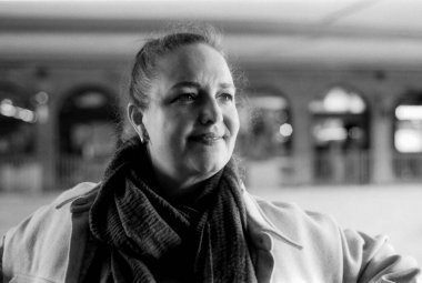 Orta yaşlı bir kadının eşarp ve palto takıp gülümseyen ve yüzünü çeviren, bulanık bir geçmişi olan, tek renkli, tek renkli bir fotoğraf.