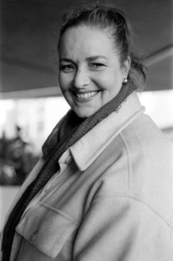 Yüzünde eşarp ve ceket olan gülümseyen orta yaşlı bir kadının 35 mm 'lik sığ bir tarla derinliğinde çekilmiş tek renkli portresi.