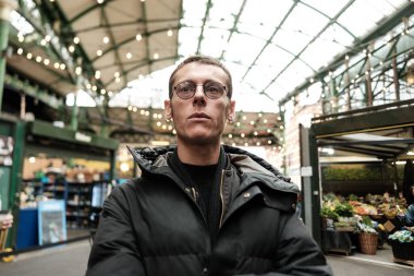 Borough pazarında çapraz silahlarla poz veren kendine güvenen genç bir adamın portresi, Güney Wark, Londra 'da popüler bir toptan satış ve perakende gıda pazarı.