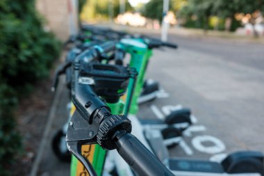 Paylaşılan elektrikli scooterların gidonları ve kontrolleri şehir caddesi boyunca hizalanarak, modern şehir yaşamında kentsel ulaşım ve hareketliliği artırmak için uygun seçenekler sunuyor.