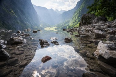 Dağların ve yüksek taş duvarların arasına yuva yapmış el değmemiş dağlık göl, Obersee, Almanya.