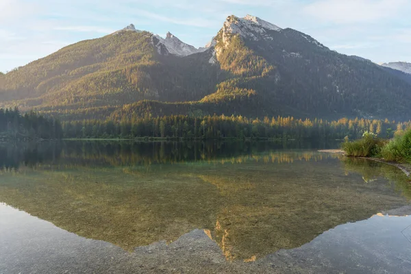 Majestic mountain reflected in still alpine lake during sunrise, Hintersee, Germany.