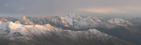 Panoramatický Záběr Zasněženého Pohoří Vysokými Štíty Během Oranžového Západu Slunce — Stock fotografie