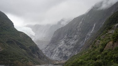 Büyük buzulun geniş bir görüntüsü Yeni Zelanda 'da kayalık duvarların arasından bir vadiye akıyor..