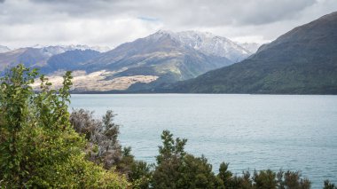 Arkaplanda karlı dağları olan Alp Gölü, Yeni Zelanda.