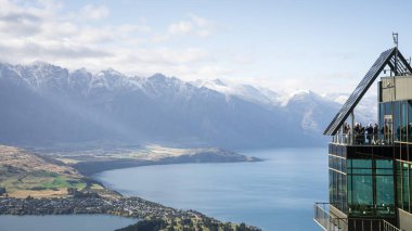 Turistler, Yeni Zelanda 'da göl kenarındaki güzel dağlık arazide manzaranın keyfini çıkarıyorlar..
