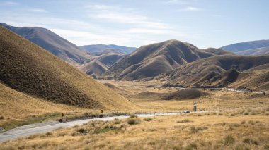 Sonbahar renklerinde yüksek dağ geçidi içinden geçen kıvrımlı otoyol, Yeni Zelanda.