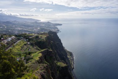 Arka planda çok yüksek uçurum ve kıyı kenti olan muhteşem manzara, Madeira, Portekiz.