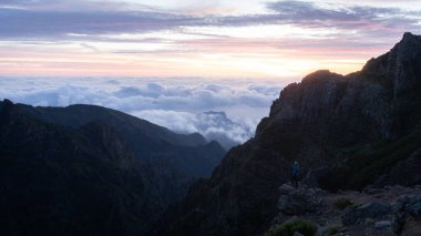Yürüyüşçü, renkli gündoğumu sırasında güzel dağlık manzaranın tadını çıkarıyor, Madeira, Portekiz.