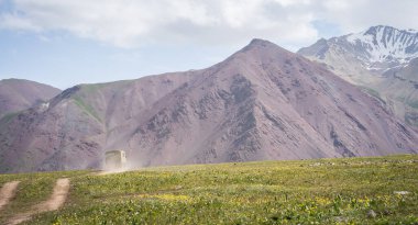 Eski ordu kamyonu tozlu bir yolda dağlara doğru gidiyor, Pamir dağları, Kırgızistan.