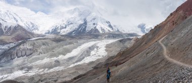 Wide panorama of valley glacier and snowy peaks with tourists hiking, Pamir mountains, Kyrgyzstan. clipart