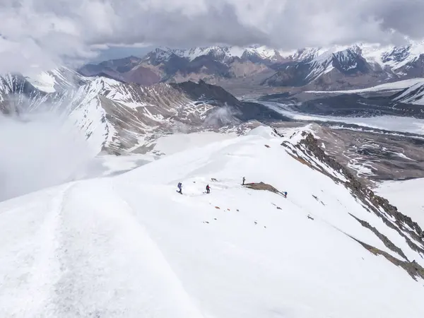 Dağcılar karlar ve dağların arasından iniyorlar, Pamir Dağları, Kırgızistan.