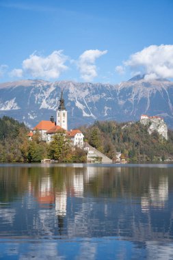 Gölün ortasındaki kilisenin dikey çekimi, arka planda şato, Bled, Slovenya, Avrupa.