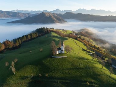 Tepedeki resim gibi küçük kilise. Arka planda sisli dağlar, Slovenya, Avrupa..