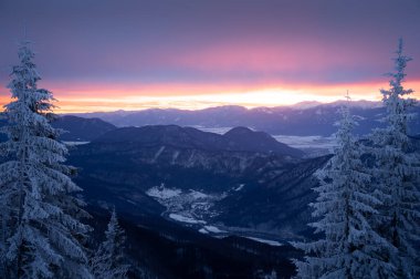 Karlı dağlarla ve renkli gündoğumu sırasında vadilerle huzurlu kış manzarası, Avrupa.