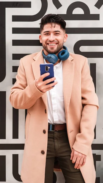 Молодой Стильный Колумбийский Мужчина Использующий Сотовый Телефон Прислонившийся Стене — стоковое фото