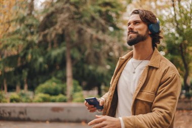 Parkta müzik dinleyen beyaz bir adamı yakından izleyin. Yüksek kalite fotoğraf.
